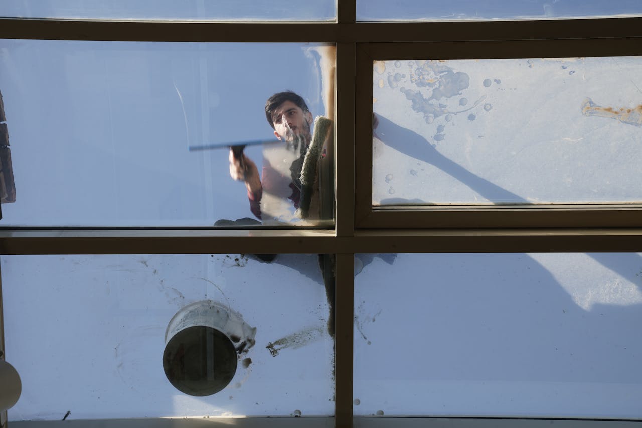 The Art of Drawing Readers In: Your attractive post title goes here A male window cleaner washing the exterior glass roof from above with a tool during daylight.