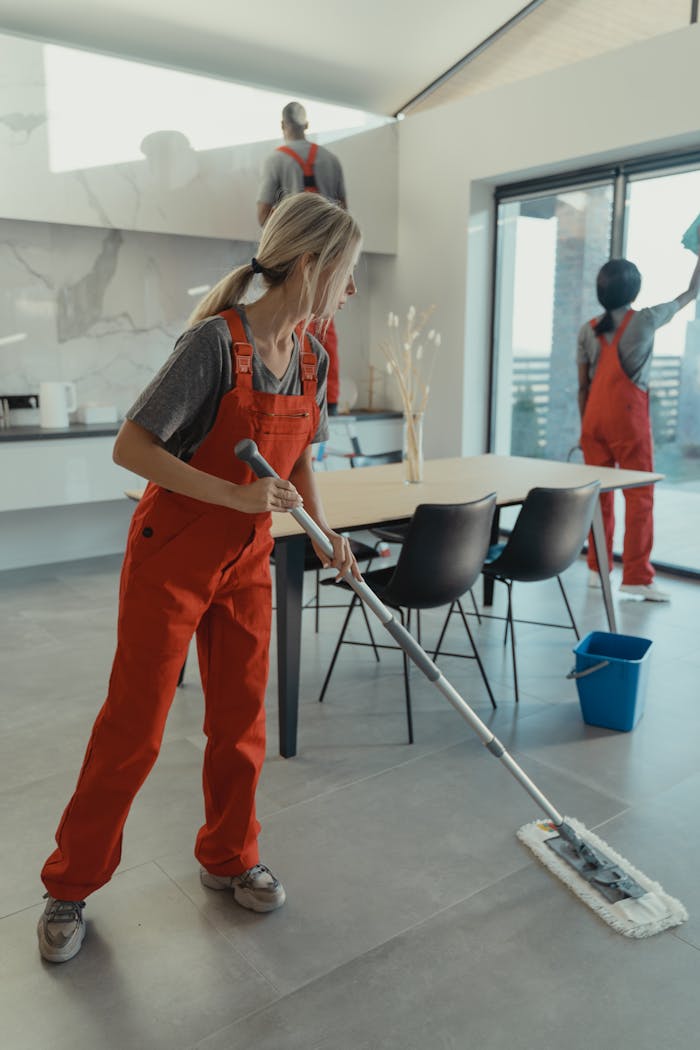 Mastering the First Impression: Your intriguing post title goes here Cleaning team in red overalls mopping and sanitizing a modern home interior.